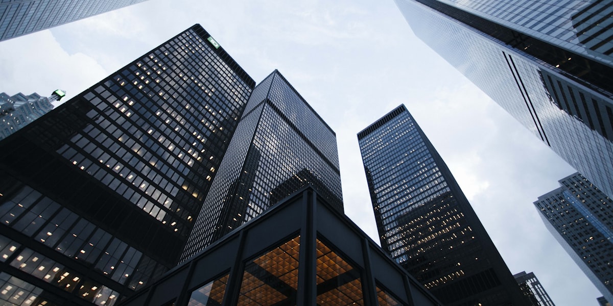 Looking up at financial district skyscrapers against a bright sky, representing the equity market rebound