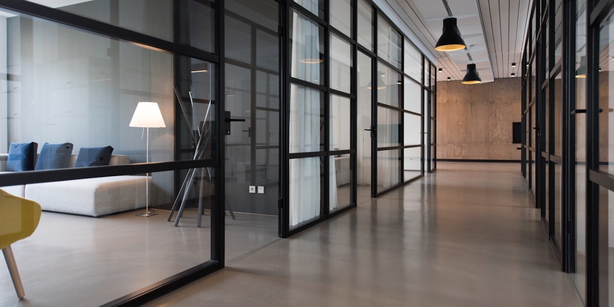 Empty glass-walled office corridor, representing margin compression and deeper cuts at Tier-2 IT firms